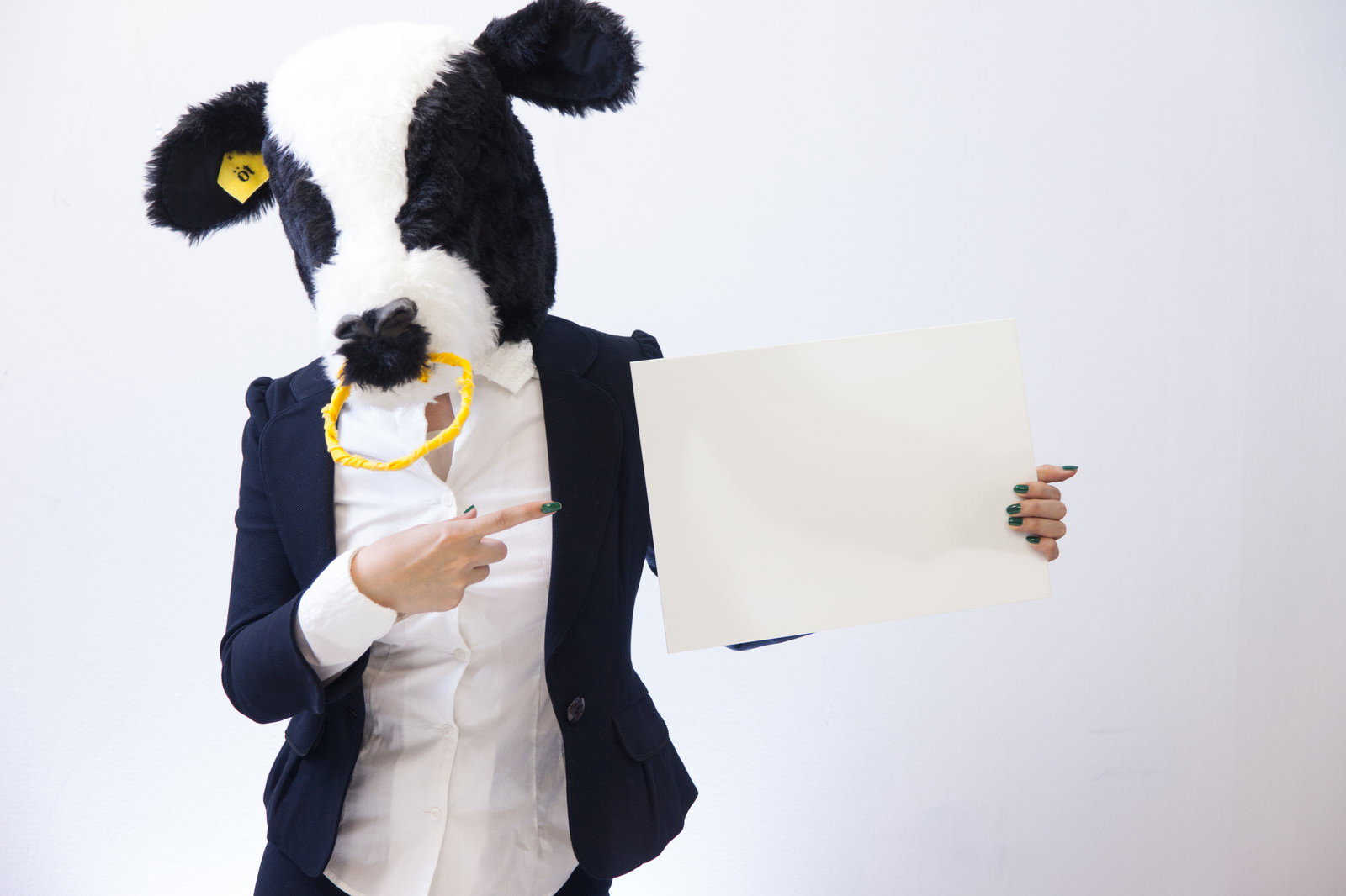 牛の被り物をした人物が白いフリップを指でさしている［モデル：古性のっち］