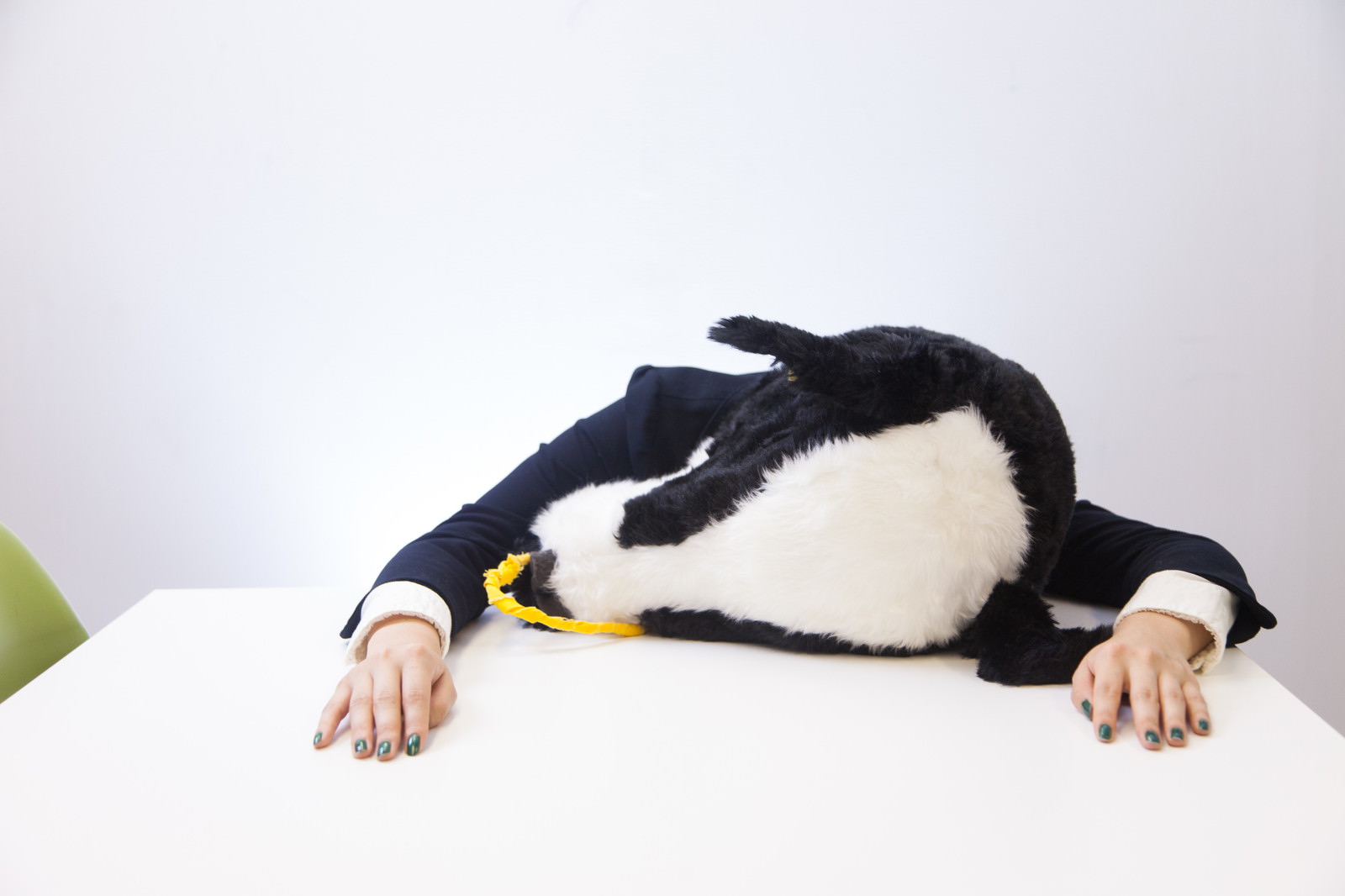 黄色いマフラーを巻いて白いテーブルに伏せるぐったりした牛人間［モデル：古性のっち］