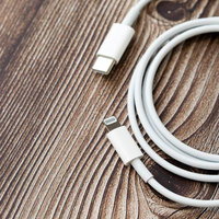 木目調の背景に置かれたUSB-Cの白いライトニングケーブルの写真