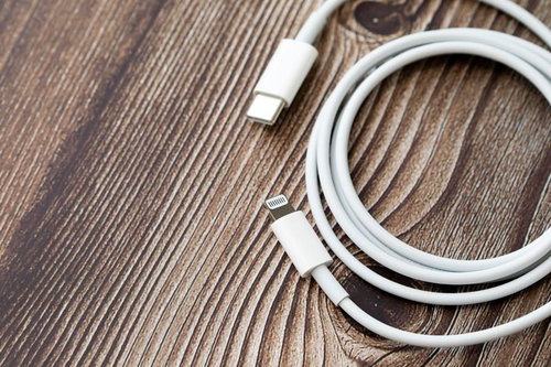 木目調の背景に置かれたUSB-Cの白いライトニングケーブル