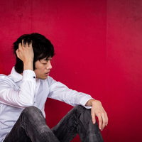 赤字経営で頭痛を抱えるフリーランス男性の経営課題の写真