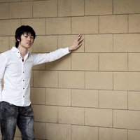 ひとり壁ドン、白シャツ姿で腕を伸ばす男性の写真