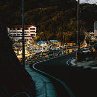 カーブを描く道路の先に広がる三重県答志島の漁港と朝焼けの写真