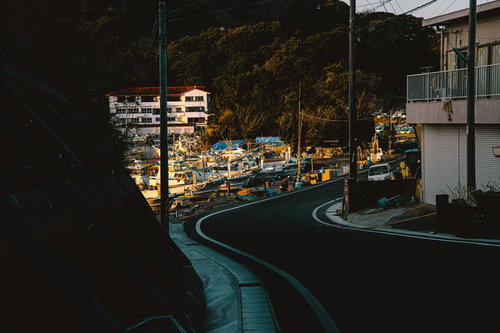 カーブを描く道路の先に広がる三重県答志島の漁港と朝焼け