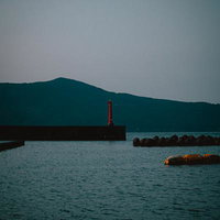 三重県答志島の和具港を照らす赤い灯台と防波堤の写真