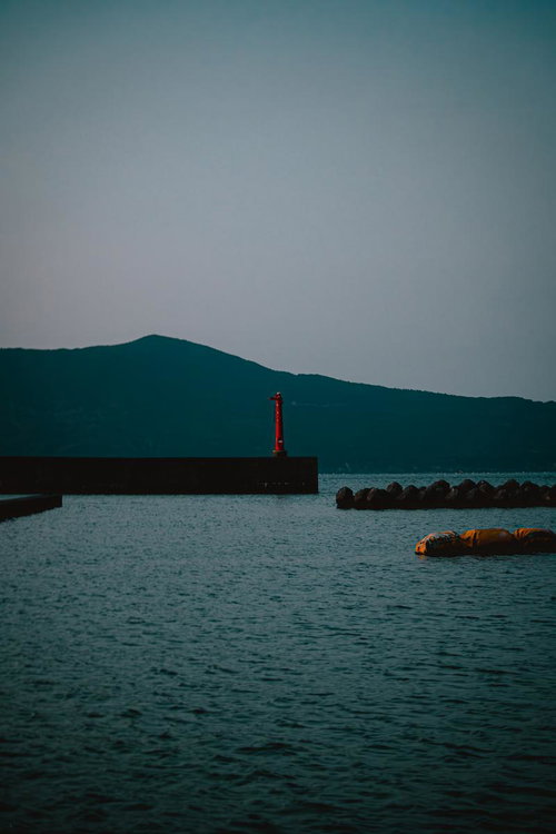 三重県答志島の和具港を照らす赤い灯台と防波堤