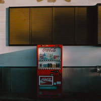 片隅に佇むレトロな赤いコカコーラの自販機の写真