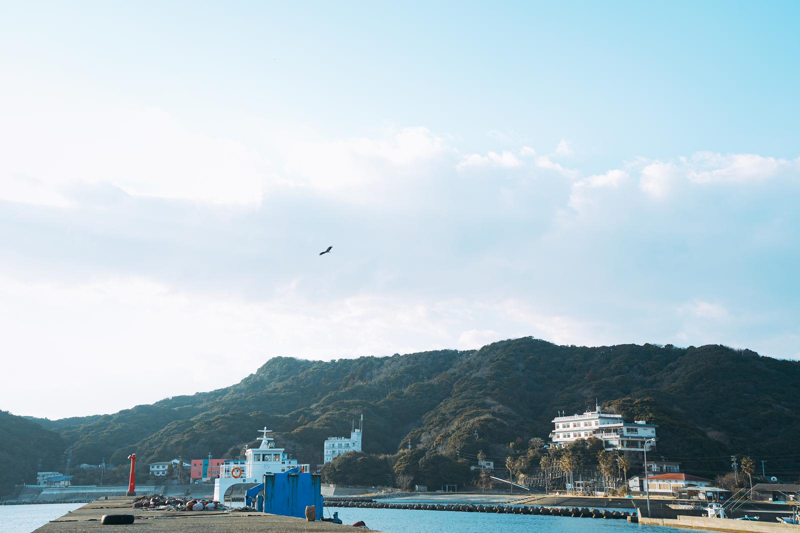 三重県答志島の港に停泊するフェリーと緑の山々を背景にした風景