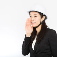 ヘルメットをかぶって大声で呼びかける女性社員の写真