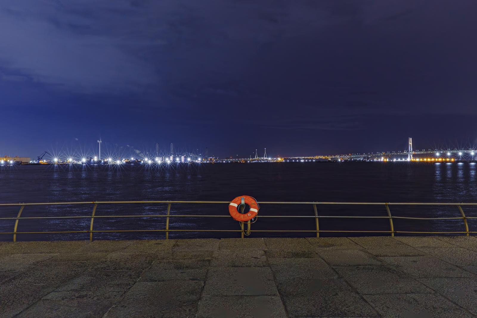 People walking along the promenade at the Yokohama Minato Mirai area during sunset, with the high-rise buildings in the background