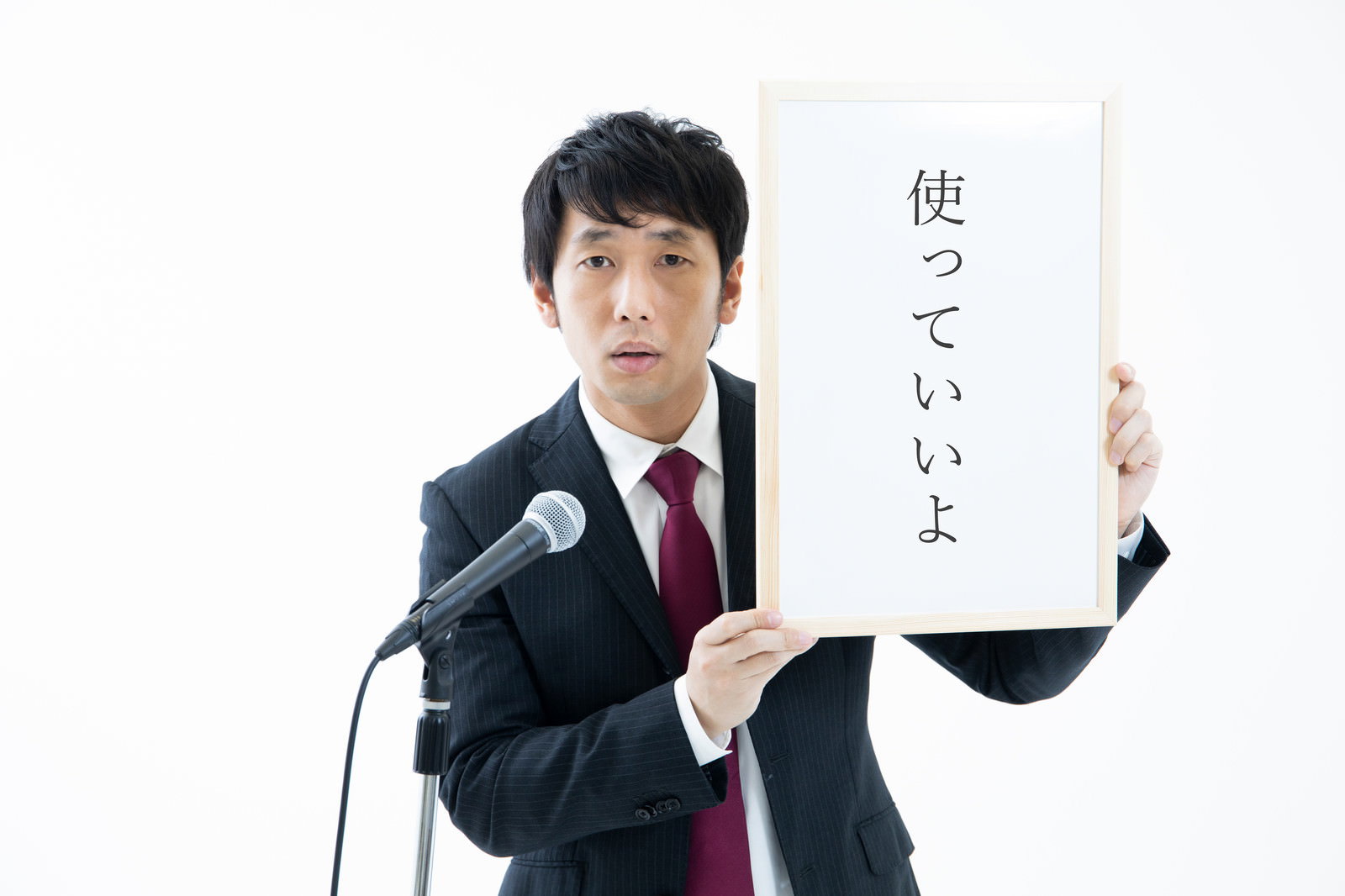 記者会見風にホワイトボードを掲げる男性［モデル：大川竜弥］