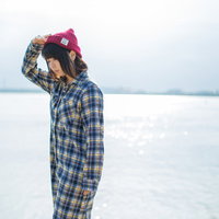 日差しと水面の反射が強い湖畔で紫外線を気にする女性の写真