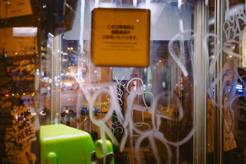 夜間の街角に立つ落書きに囲まれた電話ボックス