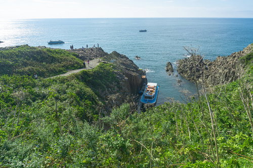 歩道から見た東尋坊観光遊覧船の乗り場に停泊中の遊覧船と沖を行く遊覧中の船