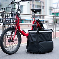 赤い自転車に設置されたフードデリバリーのバッグの写真