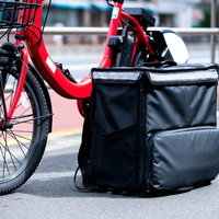 赤い自転車に設置されたフードデリバリー用の四角い保温バッグの写真