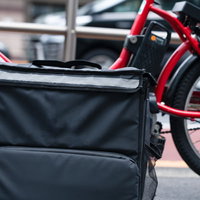 グレーのデリバリーバッグを取り付けた赤い自転車の写真