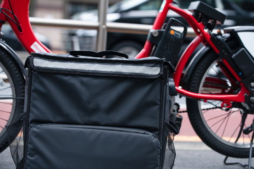 グレーのデリバリーバッグを取り付けた赤い自転車