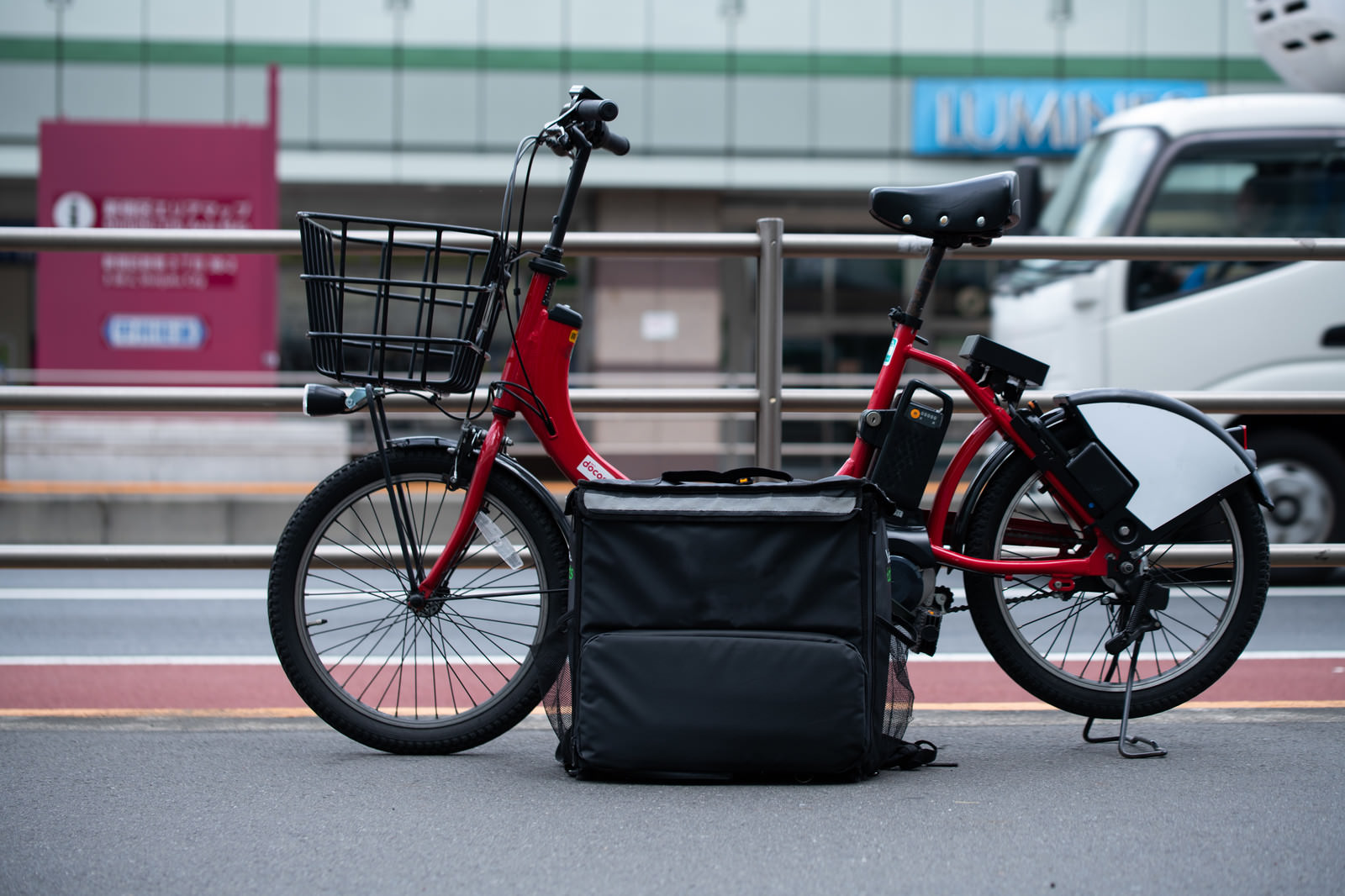 路上に停車したフードデリバリー用の赤い自転車とデリバリーバッグ