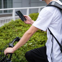 白いTシャツの配達員がスマホで配達先を調べるの写真