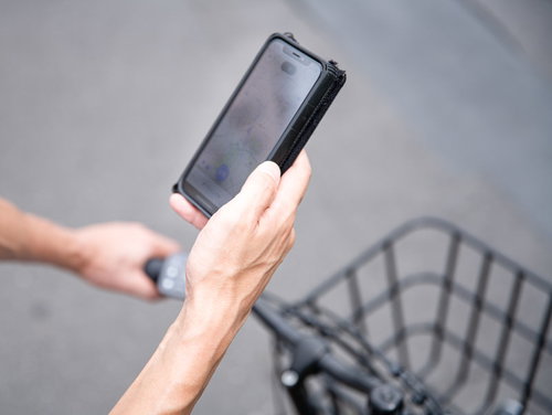 自転車で次の配達先をスマホの地図で調べる配達パートナー
