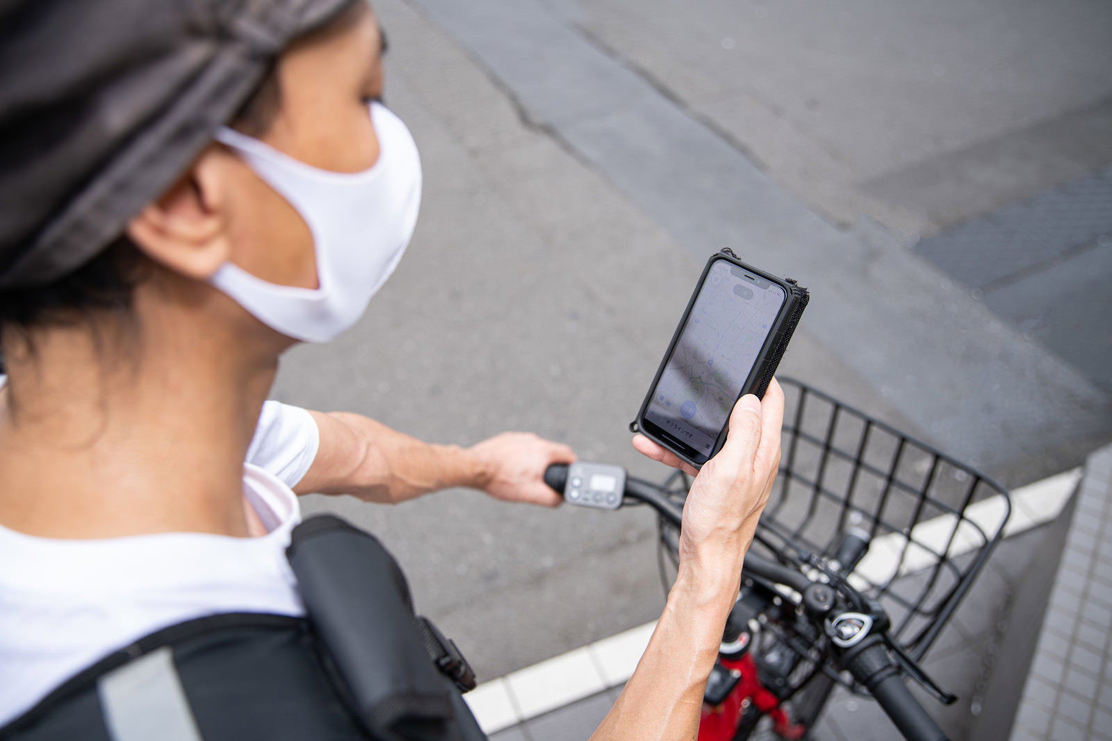 自転車にまたがりスマートフォンで地図を確認する配達パートナーの男性