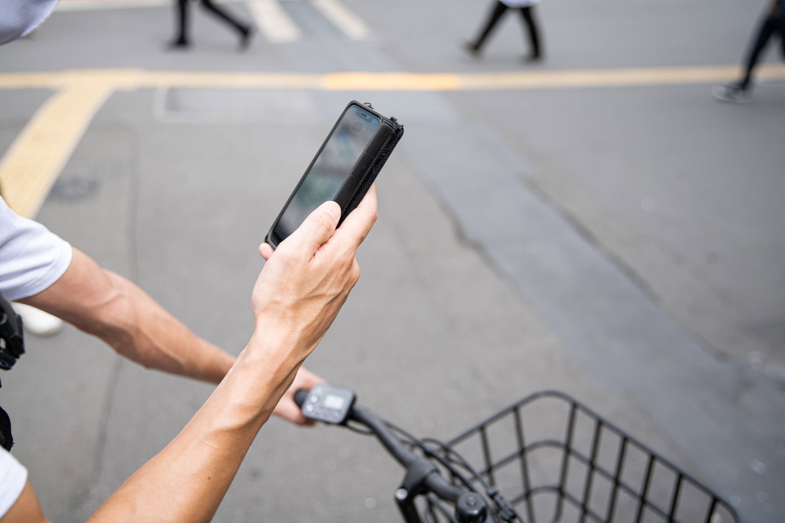 自転車のハンドルに手をかけながらスマートフォンで地図アプリを確認している人