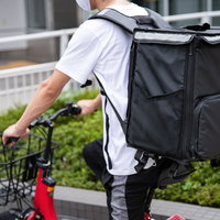 街中で見かけるフードデリバリーの配達員と赤い自転車の写真