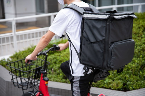 街中で見かけるフードデリバリーの配達員と赤い自転車