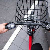 赤い電動自転車のハンドルを握る運転中の手元の写真