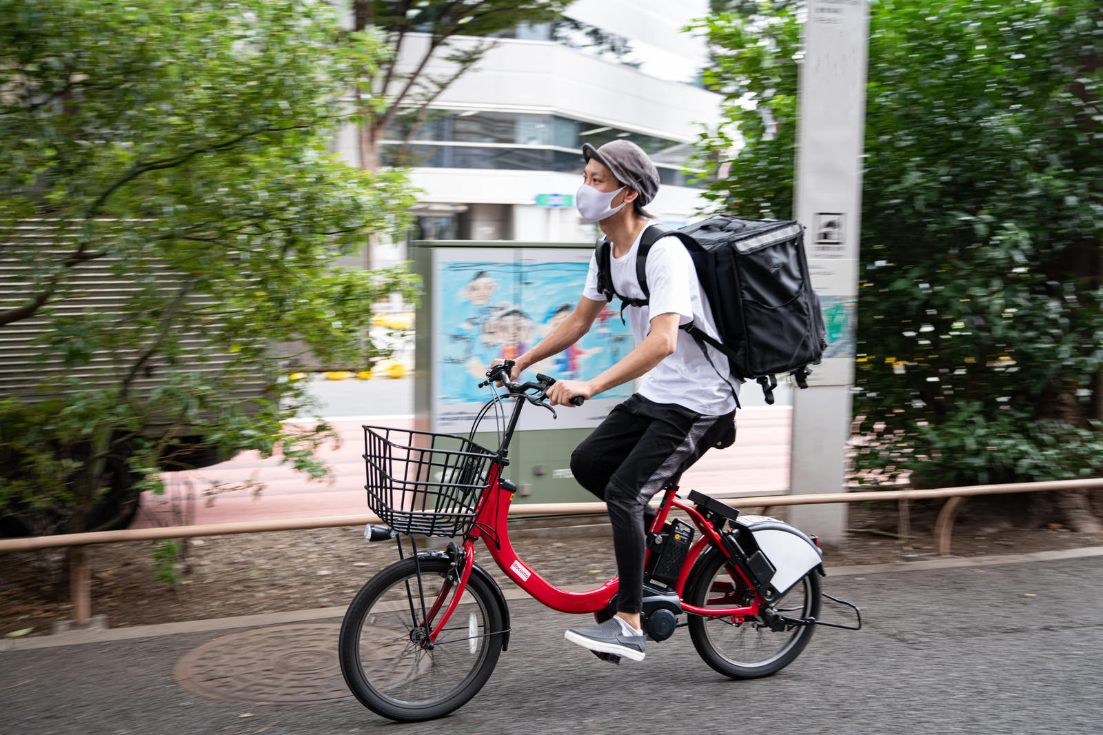 赤い自転車で配達中のフードデリバリー男性ドライバー