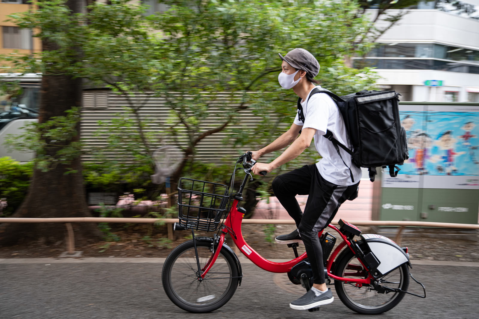フードデリバリーの配達員が赤い自転車で走行中
