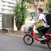 赤い自転車で配達する男性配達員の姿の写真