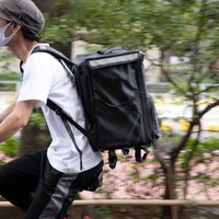 黒いリュックを背負って自転車で配達に向かう配達員の写真