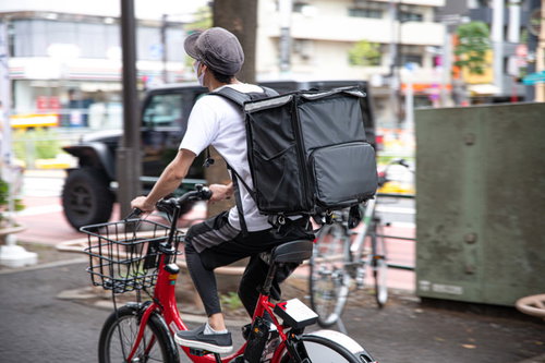 フードデリバリーの配達員が赤い自転車で配達パートナーとして運転する