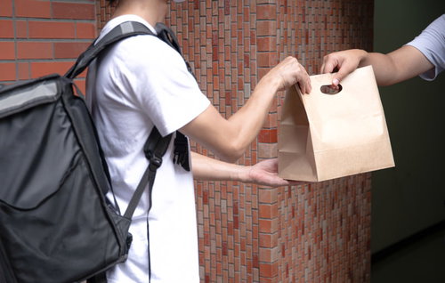 ご自宅まで注文した商品を届ける配達員と紙袋の受け渡し