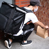 玄関先に紙袋を置き配する配達パートナーの配達風景の写真