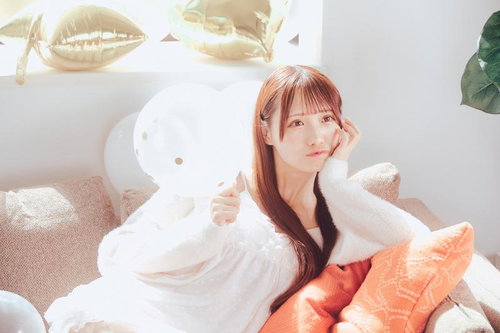 白いバルーンとソファーでくつろぐ赤褐色髪の女性