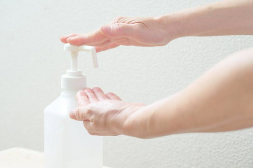 白いプッシュポンプボトルを使用して手の消毒をしている様子