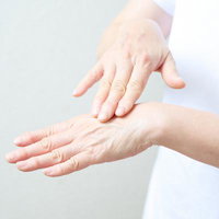 手の甲に保湿クリームを塗る女性のハンドケアシーンの写真