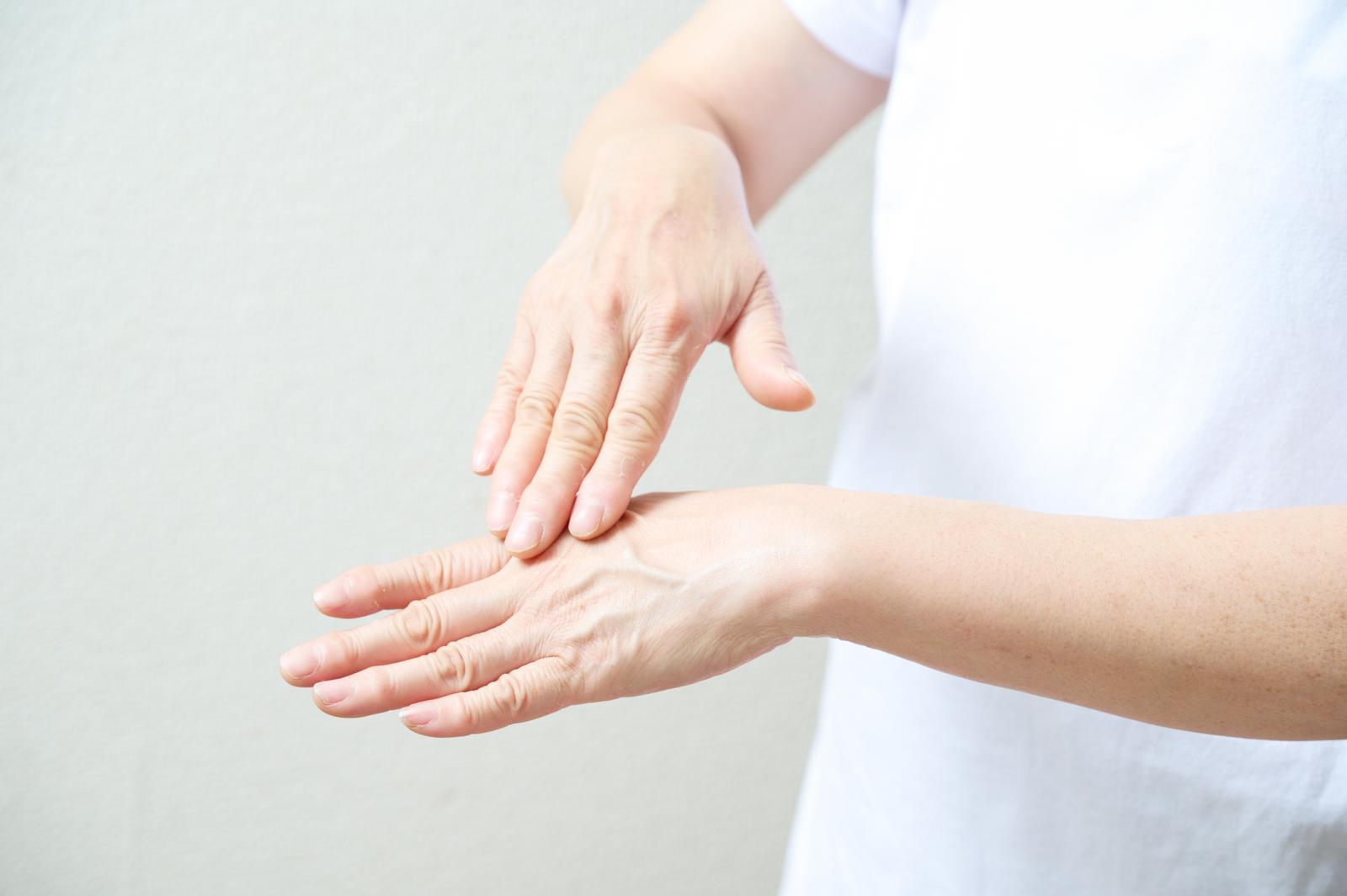 白いクリームを手の甲に塗る女性の手