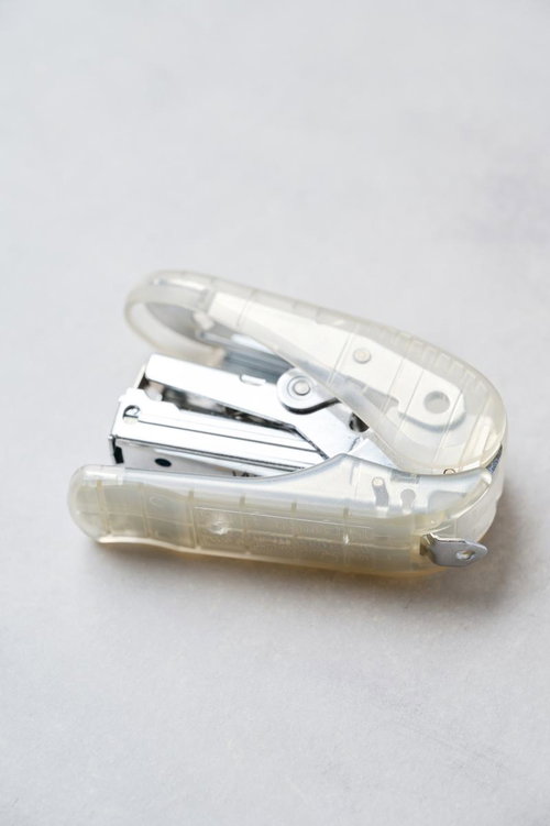 デスク上の透明ボディのホッチキスと白い書類の