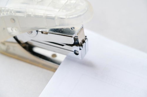 用紙に落ちるホッチキスの影と機械部分、装填されたステープル