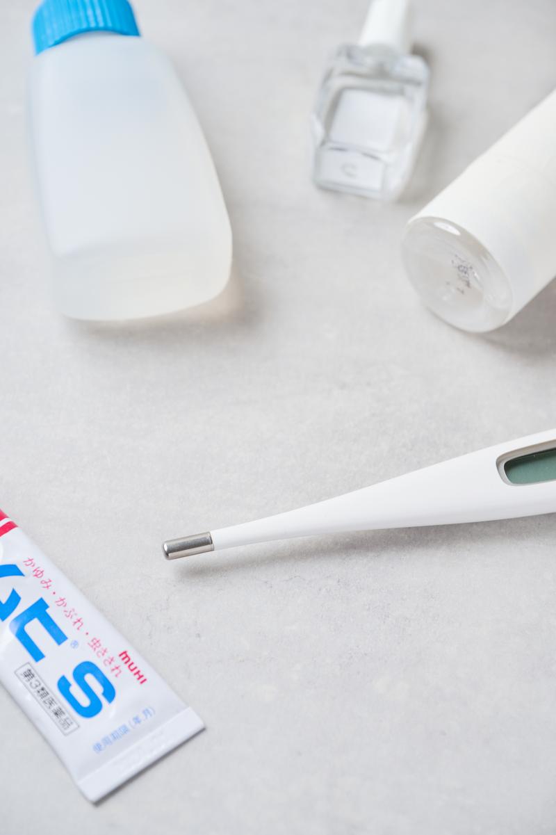 デジタル体温計と複数の常備薬が白い背景に置かれている