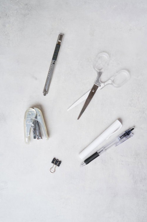 デスクに広げた筆記用具と文具セット、カッターやハサミなど