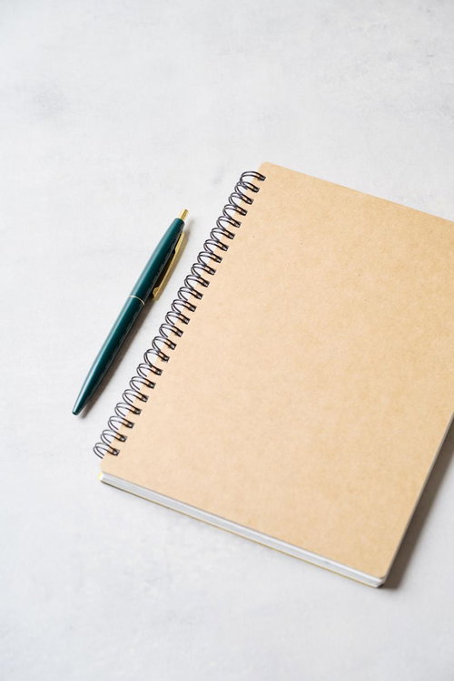クラフト紙のスパイラルノートに添えた深緑のボールペン