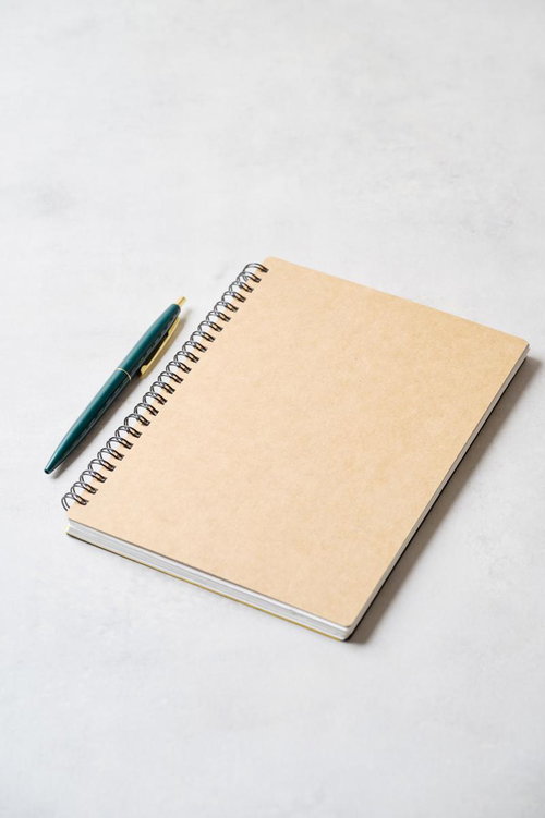 クリーム色のスパイラルノートと紺色ボールペン