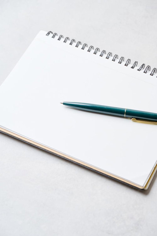 開いたスパイラルノートと緑色のボールペン