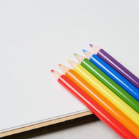 カラフルな色鉛筆が並ぶ白いノートの上のの写真