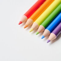 白い背景に並ぶ虹色に削られた色鉛筆の写真